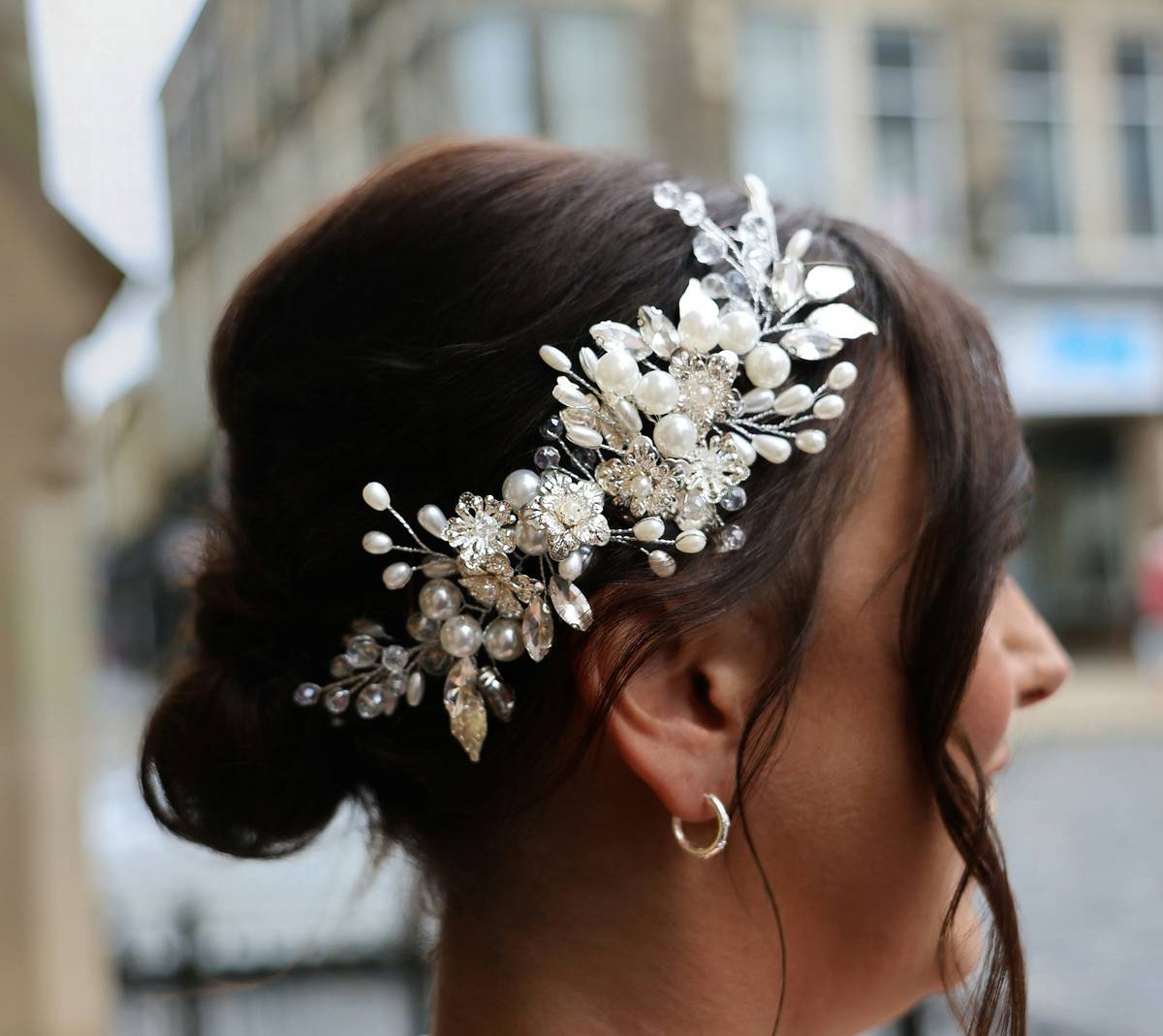 delicate bridal hairbands: close-up of a matte gold wire hairband with tiny seed pearls and woven silk ribbons, pinned into low-chignon updo on light-blonde hair